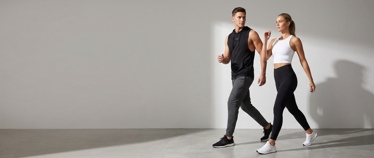 Man and woman wearing VAR activewear walking side by side in a minimalist studio
